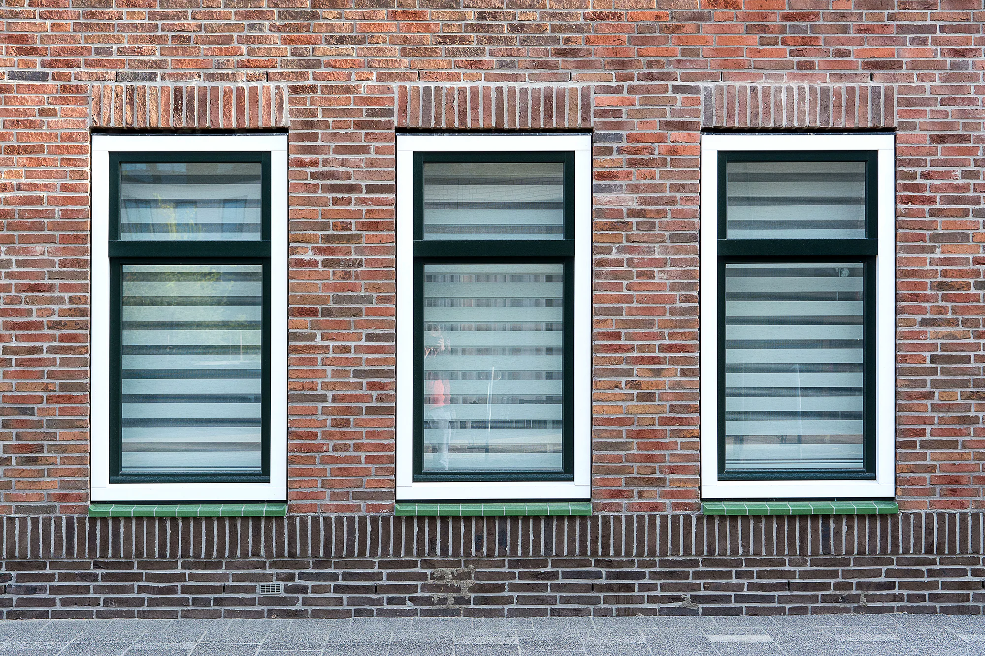 Witte kunststof kozijnen met isolerend glas in een Nederlandse bakstenen gevel