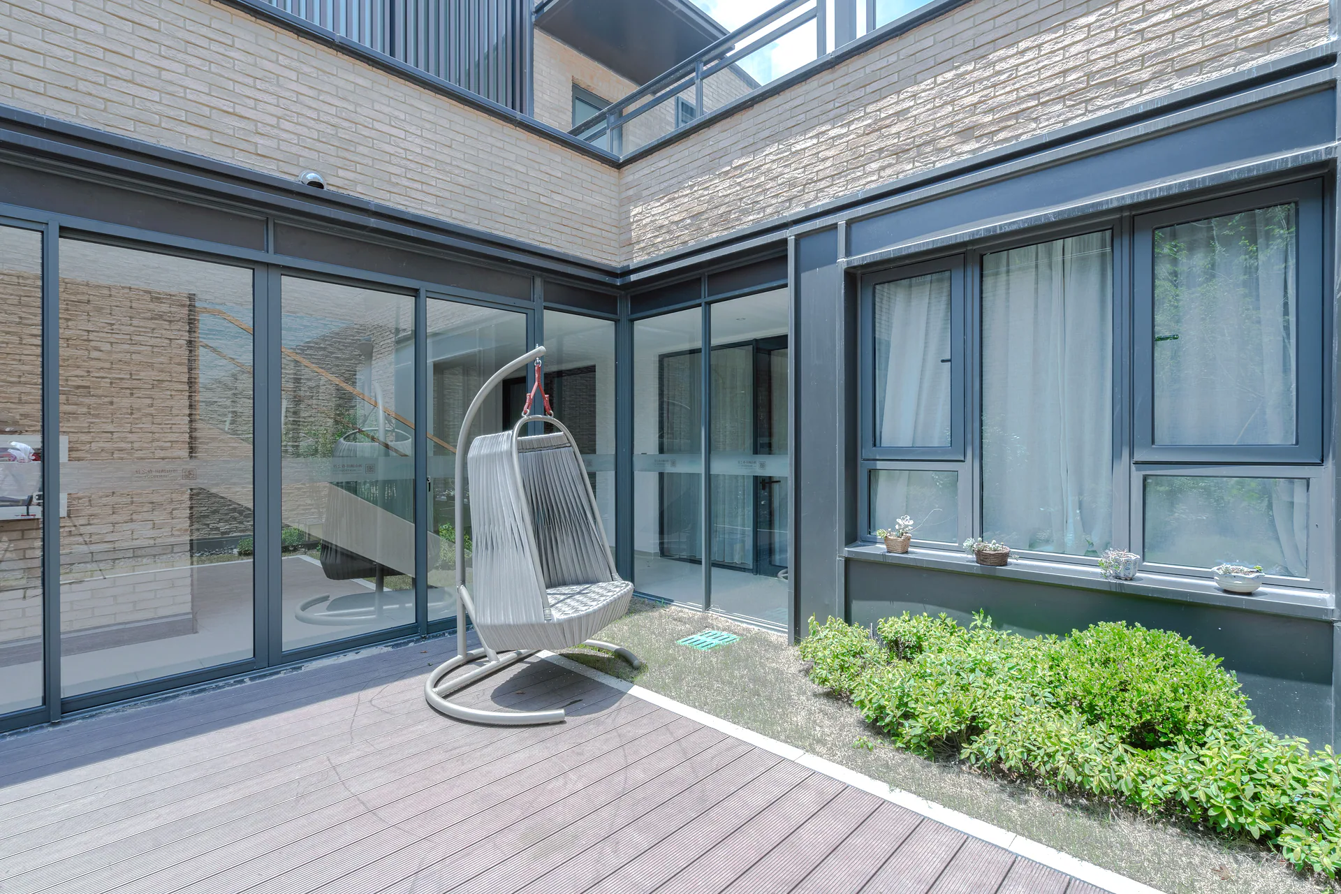 Antraciet schuifpui op de hoek van een terras, met slanke kaders en zicht naar de tuin