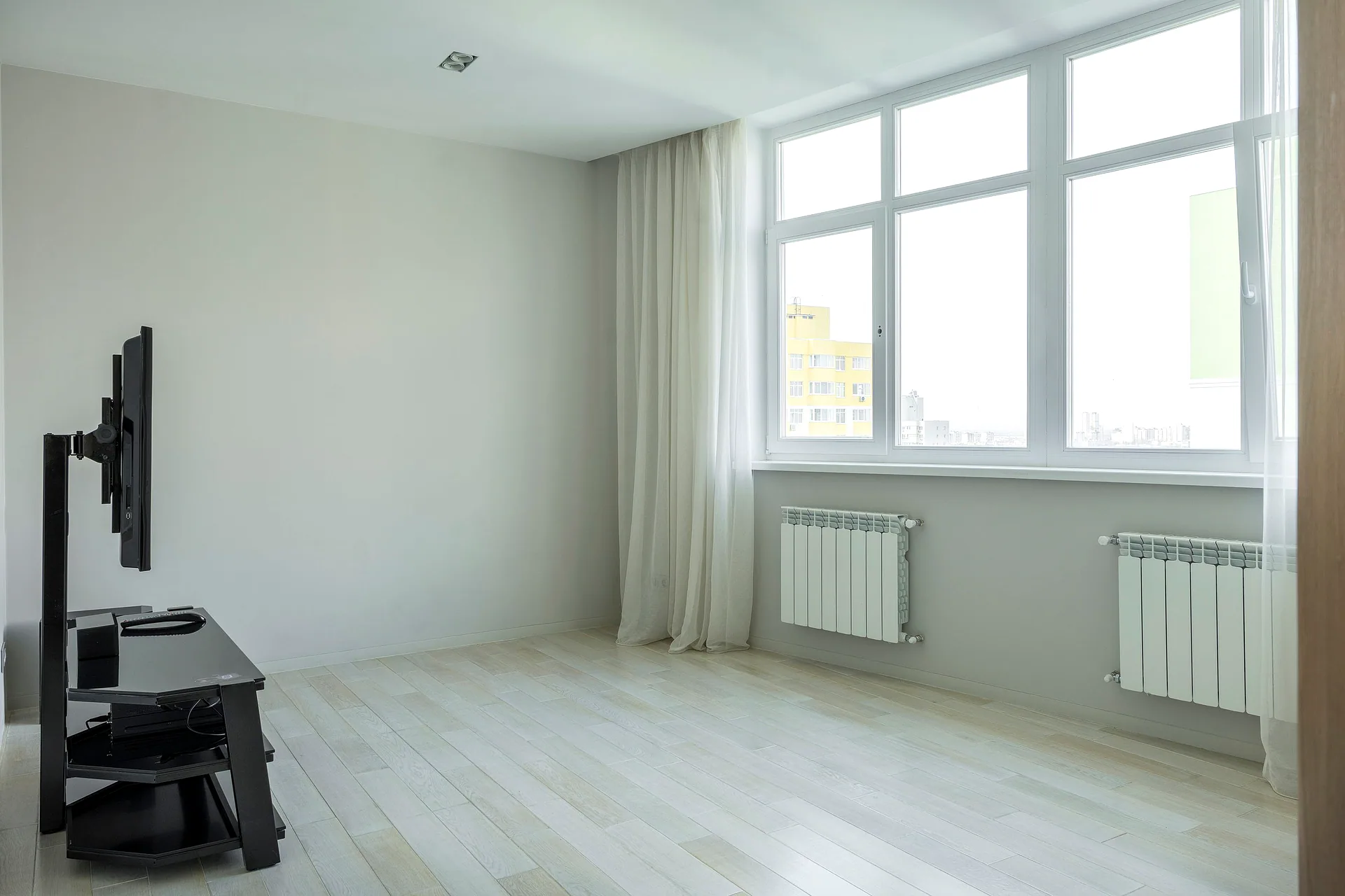 Close-up van een wit raam met zichtbare greep en isolerend glas, uitkijkend op een woonwijk